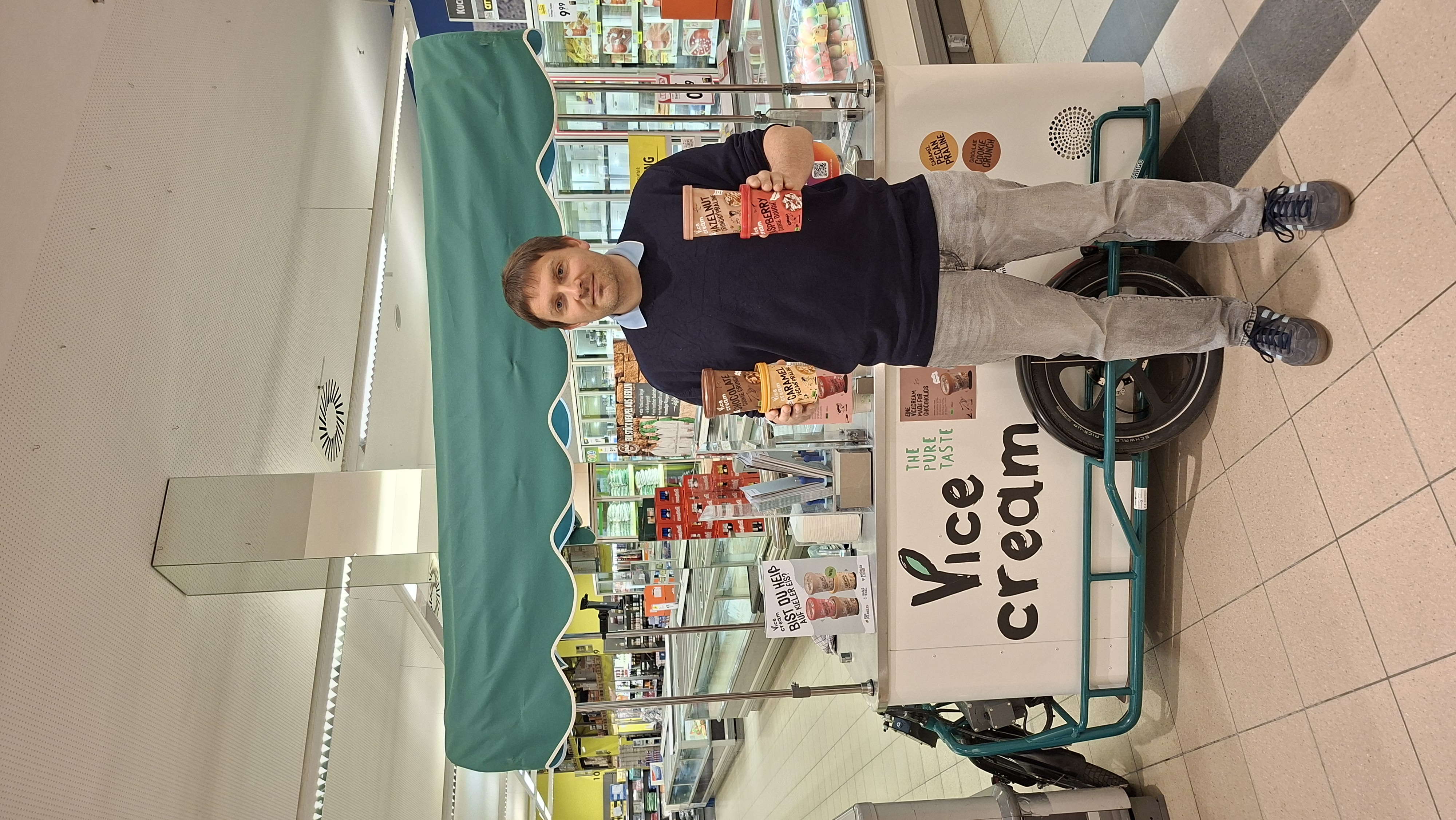Konstantin Schlecht mit Vicecream-Bechern am Eisfahrrad im Supermarkt